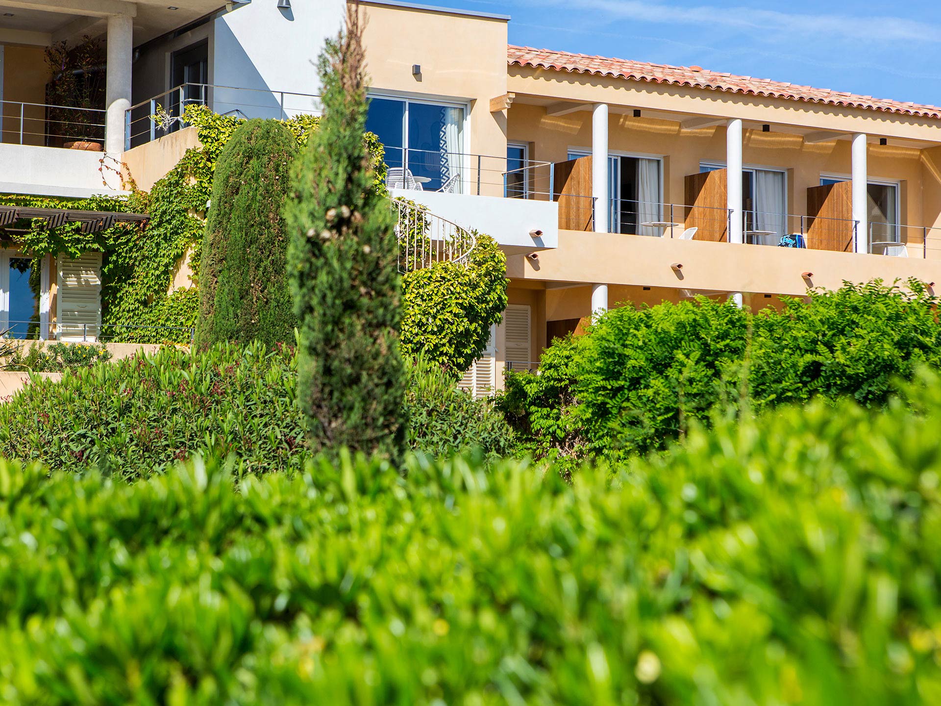 Façade d’hôtel de style méditerranéen avec balcon, vue du jardin