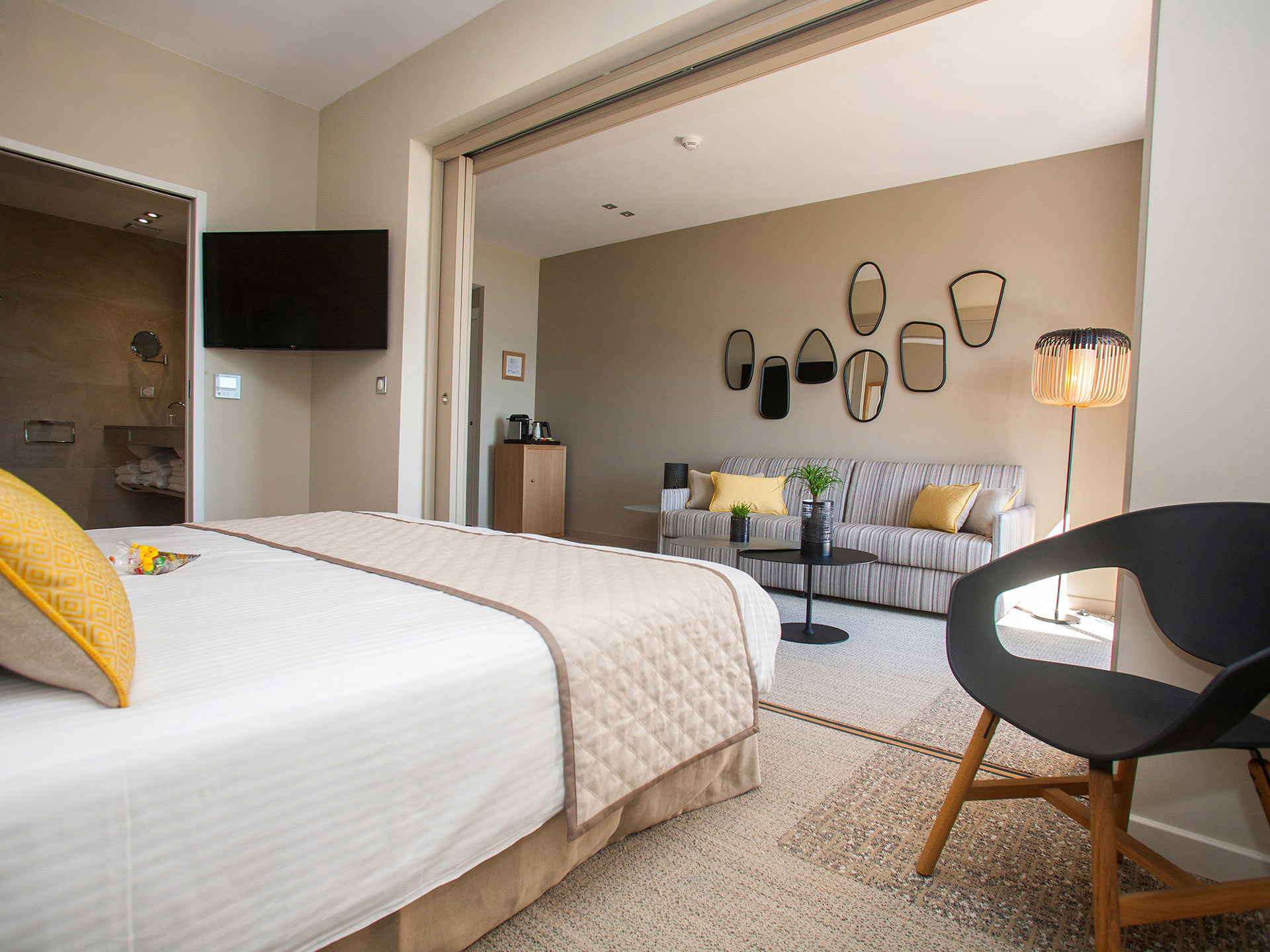 Junior suite d’hôtel moderne avec lit double, coin salon et salle de bain attenante