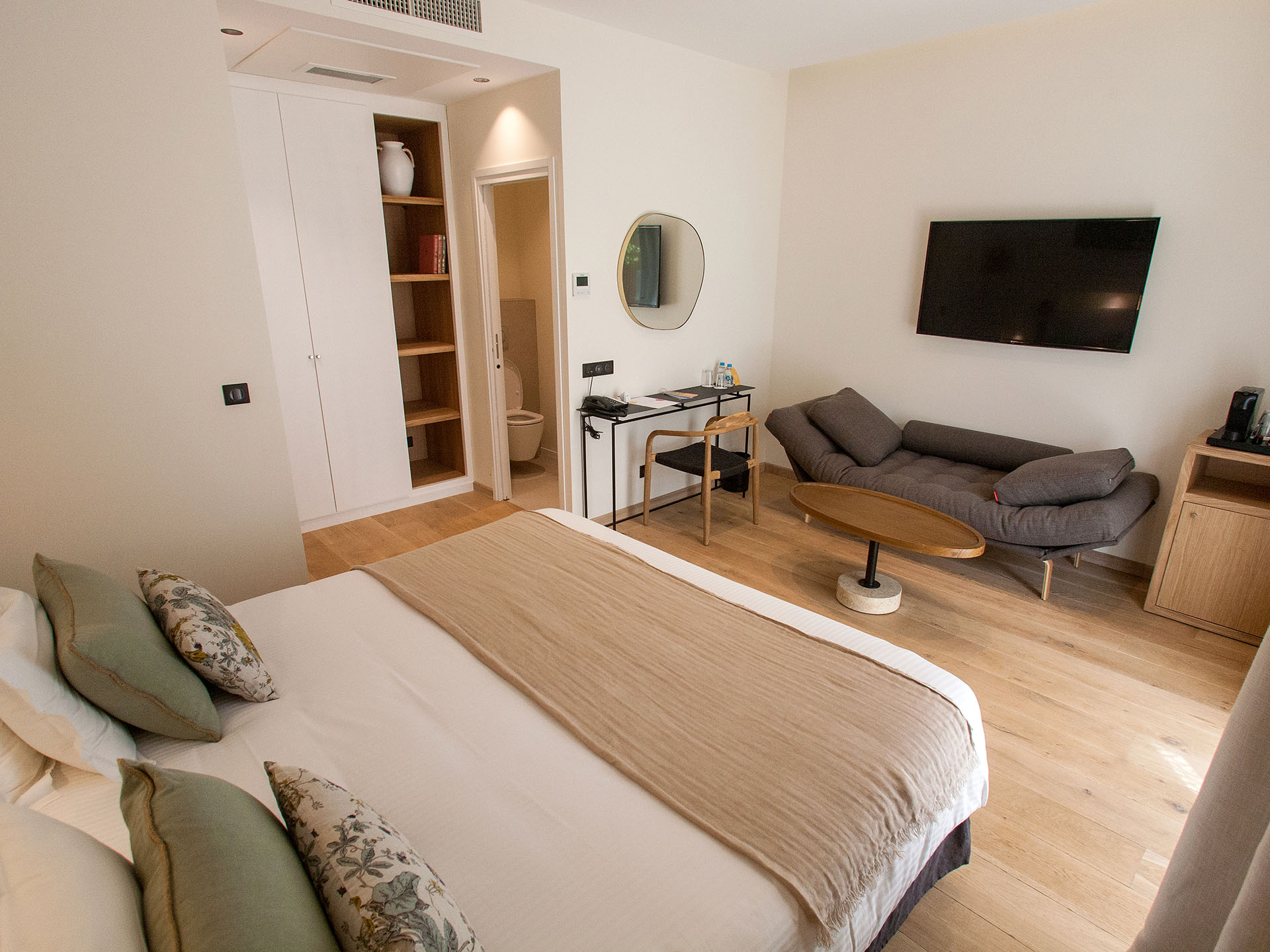 Chambre d’hôtel moderne avec lit double, coin salon, bureau et salle de bain attenante
