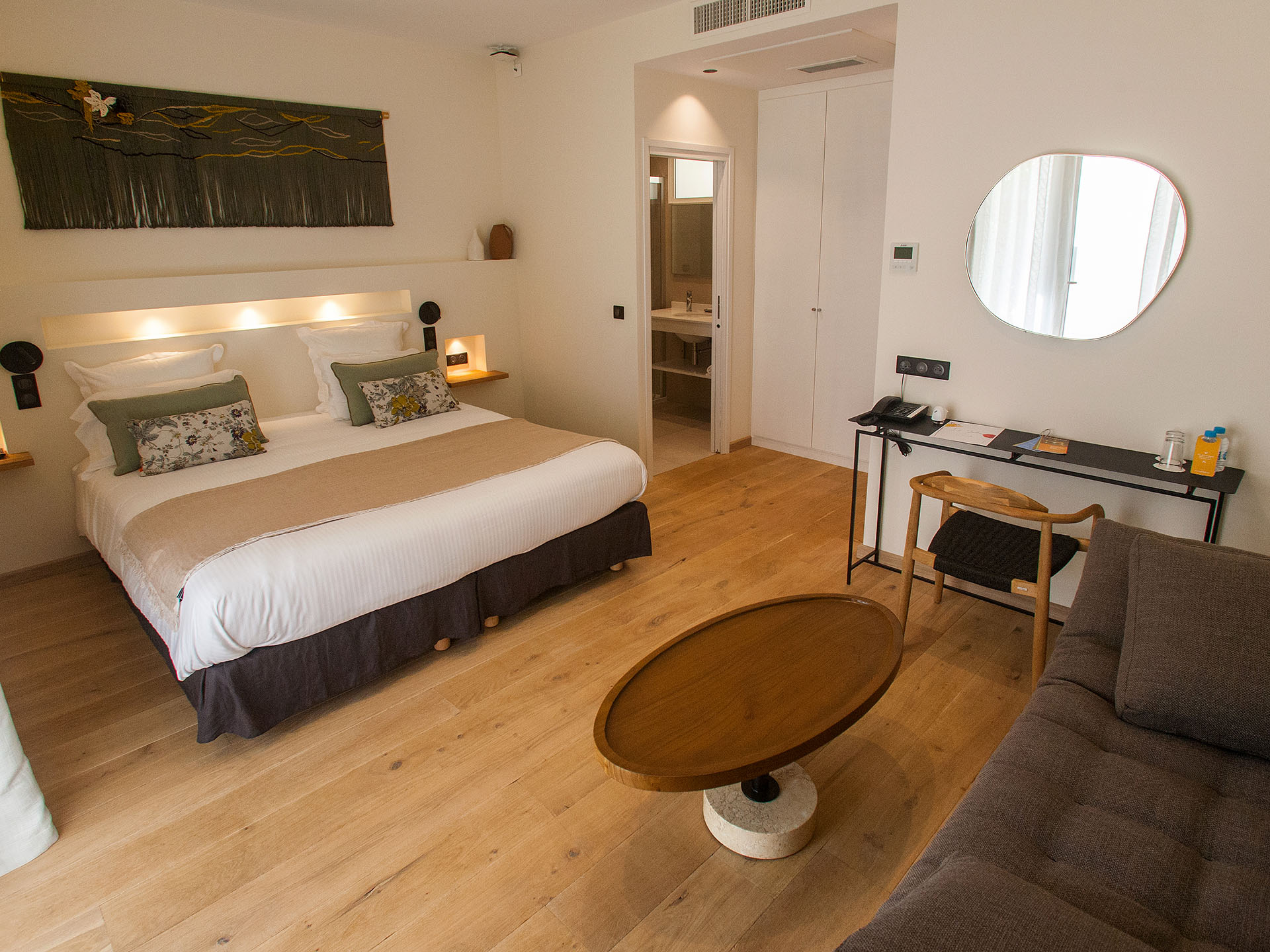 Chambre d’hôtel moderne avec lit double, coin salon, bureau et salle de bain attenante