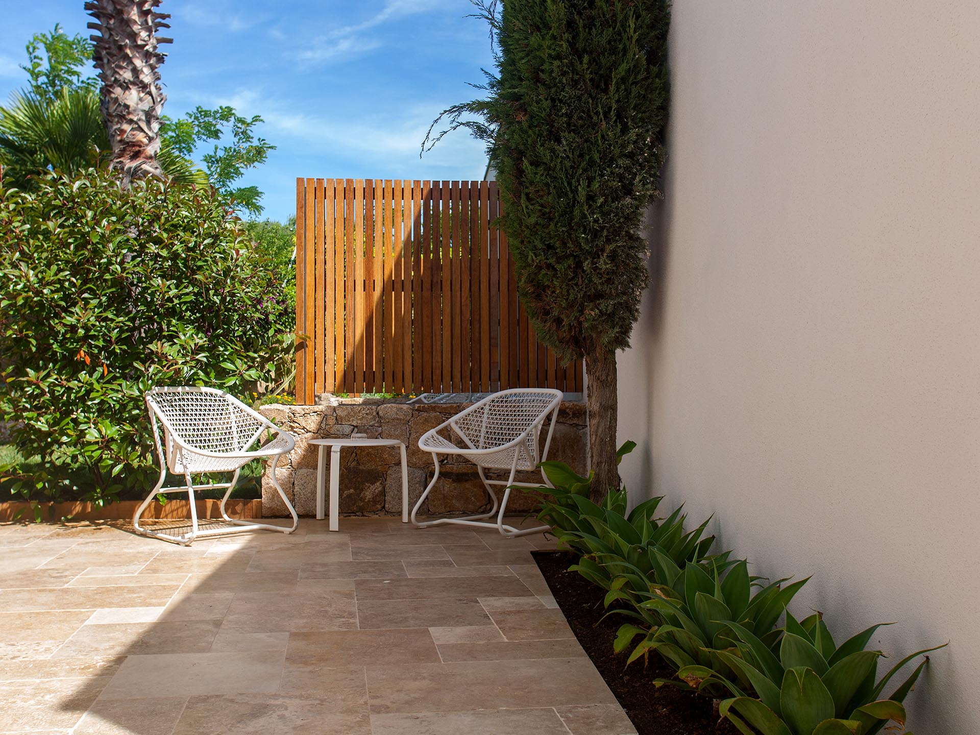 Petit patio extérieur de l’hôtel avec fauteuils blancs et jardin méditerranéen