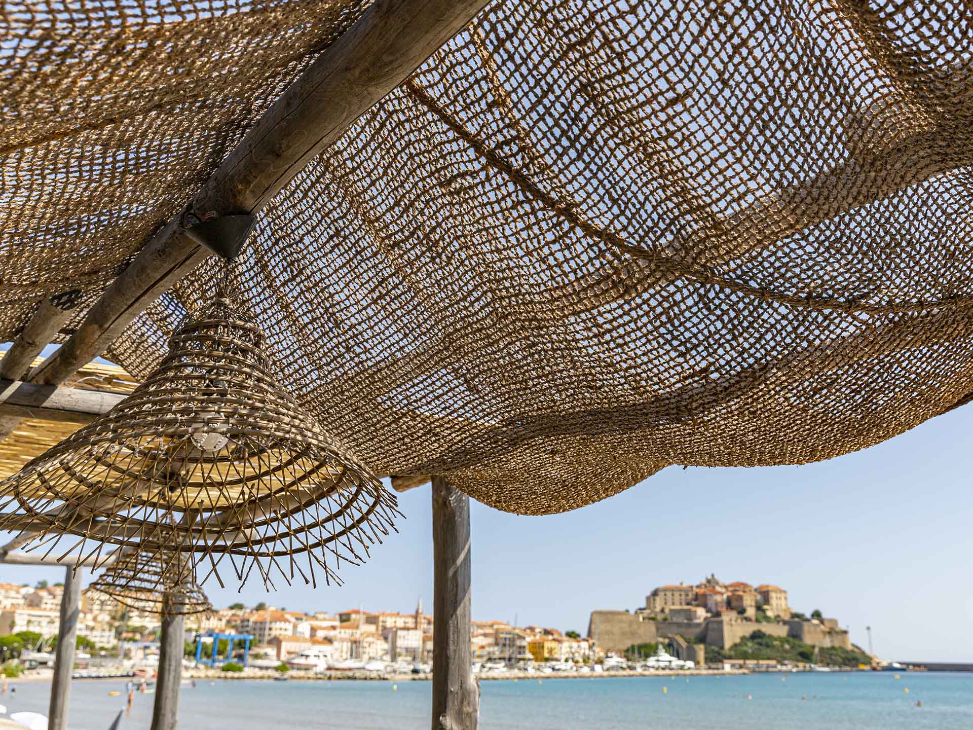 Paillote de Marco Plage avec toit tressé et vue sur la citadelle de Calvi